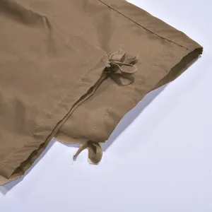 Detalle del bajo de pantalón cargo marrón con cordón, mostrando las costuras y la textura