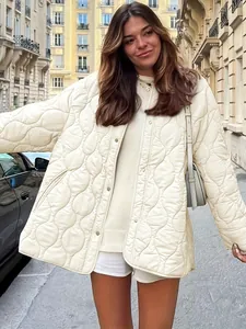Detail einer cremefarbenen Steppjacke mit Rundhalsausschnitt und Wellenmuster auf der Straße