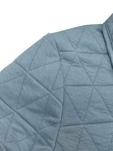 Close-up detail of blue quilted cotton jacket showing fabric texture and triangle stitching