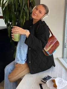 Model trägt eine schwarze gesteppte Rundhalsjacke in einem lässigen Lifestyle-Setting
