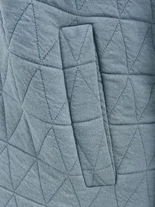 Close-up detail of quilted diamond pattern and pocket on blue winter jacket fabric