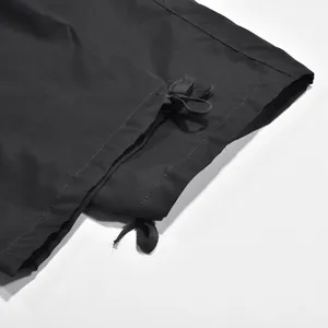 Primer plano del bajo con cordón ajustable en pantalones cargo negros para hombre.