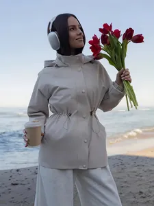 Scène lifestyle avec un coupe-vent beige imperméable pour femme sur une plage ensoleillée