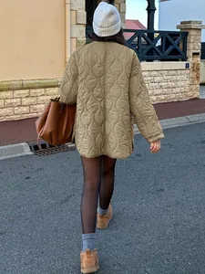 Rückansicht einer Frau in einer khakifarbenen Steppjacke in schicker Umgebung.