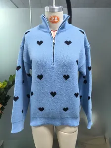 Detalle del jersey de punto azul claro con estampados de corazones negros y media cremallera.