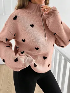 Vista detallada de un suéter de punto rosa con patrones de corazones negros y media cremallera
