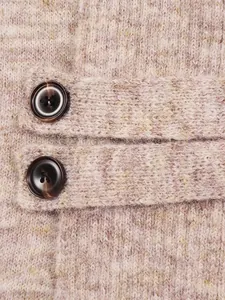 Close-up detail of soft pink knit cardigan with decorative straps and brown buttons.