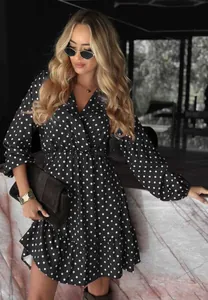 Elegant black polka dot V-neck long sleeve dress worn by a model in a stylish setting