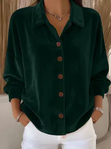 Close-up detail of emerald green velvet shirt featuring brown buttons and soft texture
