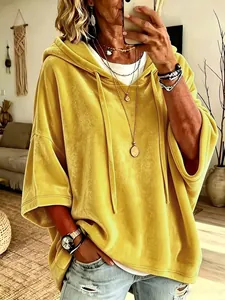 Detalle de sudadera con capucha de terciopelo amarillo con mangas tres cuartos y textura.