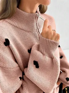 Detalle de jersey de punto rosa con estampado de corazones negros y cuello con cremallera