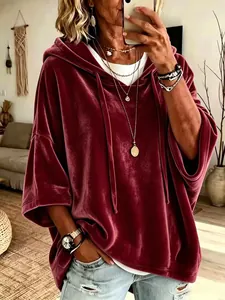Primer plano de una sudadera con capucha de terciopelo burdeos con mangas 3/4 y accesorios.