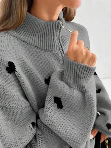 Vista detallada del jersey de punto gris con corazones negros y cuello con cremallera.