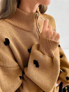 Detalle de suéter de punto con estampados de corazones negros y cremallera metálica