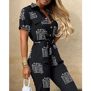 Detailed view of the script print and belted waist on a black short-sleeved jumpsuit