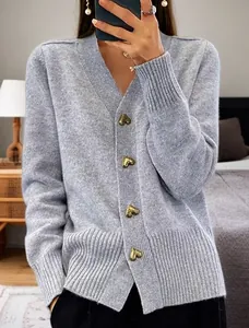 Detail view of grey V-neck knit cardigan featuring decorative gold heart-shaped buttons