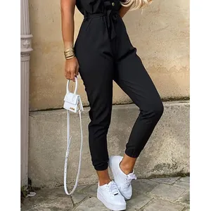 Stylish black short-sleeve jumpsuit styled with white sneakers and mini bag detail