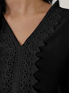 Detailaufnahme eines schwarzen Oberteils mit V-Ausschnitt und eleganter Spitzenverzierung.
