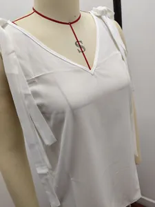 Gros plan d'un haut blanc à col en V avec des bretelles à nœuds réglables sur mannequin.