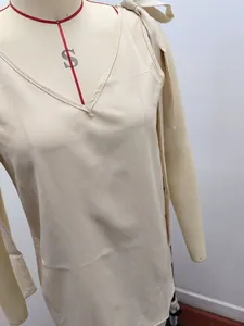 Vue détaillée d'un haut beige à col en V avec d'élégants nœuds décoratifs aux épaules