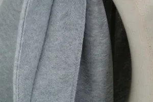 Detail macro-opname van grijze wollen stof en precisie stiksels op een wollen jas