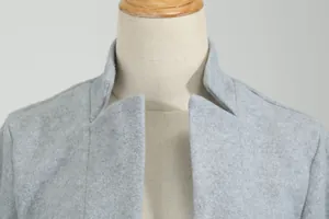 Detailopname van de opstaande kraag en zachte woltextuur van een lichtgrijze wollen jas