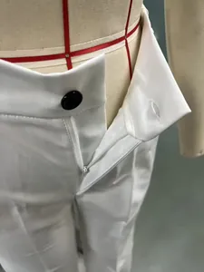 Close-up detail of white high-waist women's suit pants showing zipper and button closure