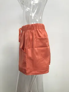 Detailed side view of orange high-waist casual shorts with pocket and drawstring