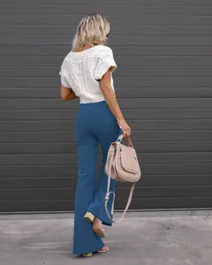 Back view of high-waist blue corduroy flare trousers paired with a white knit top