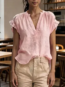 Close-up of V-neck and ruffle sleeve detail on pink bohemian cotton linen blouse