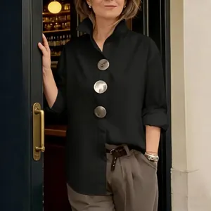 Vista detallada de la elegante camisa negra con cuello alto y tres botones metálicos grandes