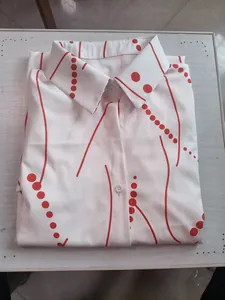 Detail view of a white elegant blouse with red polka dots and wave line pattern