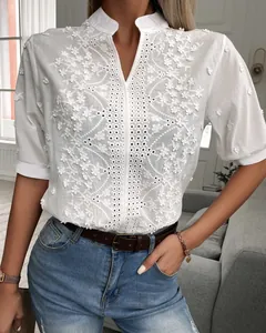 Close-up detail of white V-neck blouse with intricate floral embroidery and lace