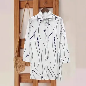 Detailed view of women's elegant white shirt dress with polka dots and wavy lines