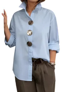 Camisa azul claro con cuello alto y tres botones metálicos decorativos de gran tamaño