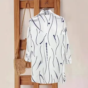 Detail of elegant long-sleeved shirt dress with blue wave and polka dot patterns.