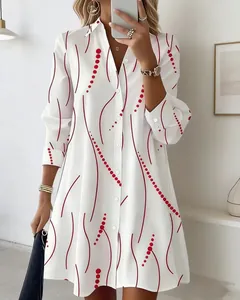 Close-up of elegant white long-sleeved shirt dress with red wave and polka dot print