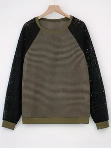 Detailweergave van de wafelgebreide textuur en zwarte kanten mouwen op olijfgroene top.