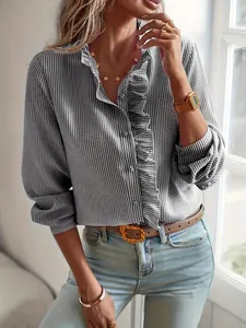 Detalle de elegante camisa de rayas grises con volantes frontales y cierre de botones.