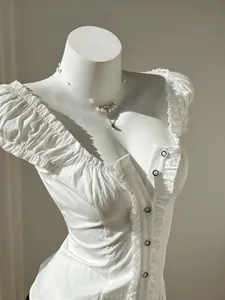 Close-up of elegant white puff sleeve blouse with ruffle trim and button front detail.