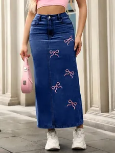 Close-up of long denim skirt featuring delicate pink bow embroidery for a trendy look.