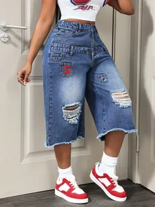 Detail of trendy distressed blue denim culottes with raw hems and patch design for women.