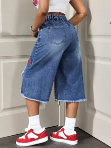 Close-up detail of women's distressed denim culottes featuring raw hem and S patch