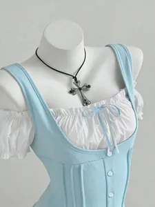 Close-up detail of light blue and white patchwork top with bow and ruffled sleeves
