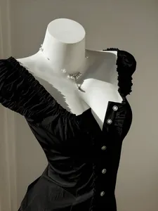 Detail view of black puff sleeve blouse with white buttons shown on white mannequin