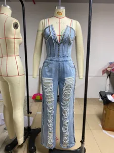Mono de mezclilla azul claro con tachuelas y piernas rasgadas en un maniquí de costura.