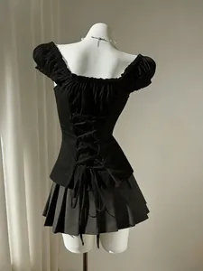 Rear view of elegant black puff sleeve blouse with lace-up back detailing on white mannequin