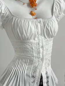 Vista dettagliata della camicia bianca con scollo quadrato, maniche a sbuffo e bordo in pizzo