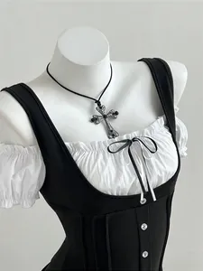 Detail of a chic black and white patchwork slim-fit top with a bow and button accents.