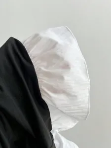 Close-up detail of black stretch T-shirt with white poplin patchwork puff sleeve design